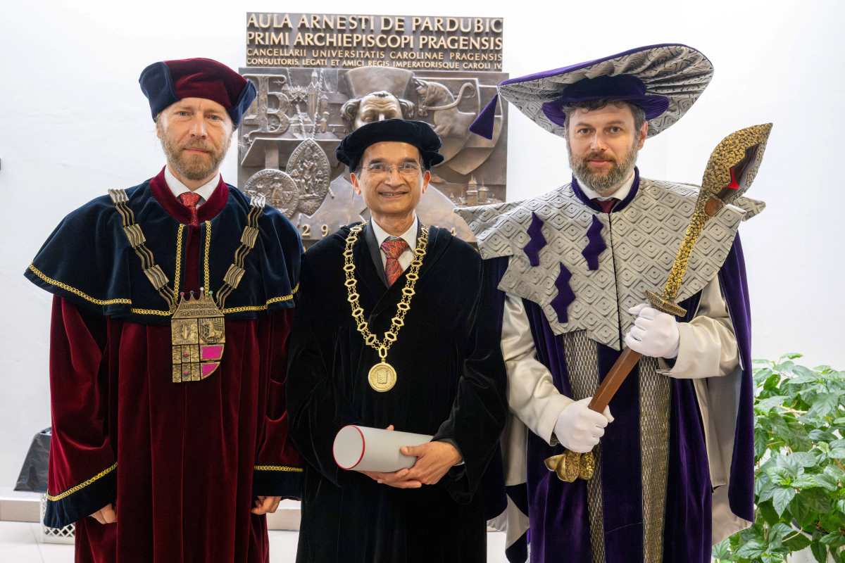 Three men standing in full academic regalia - Dr. Jain is in the center wearing a medal and holding his honorary doctorate