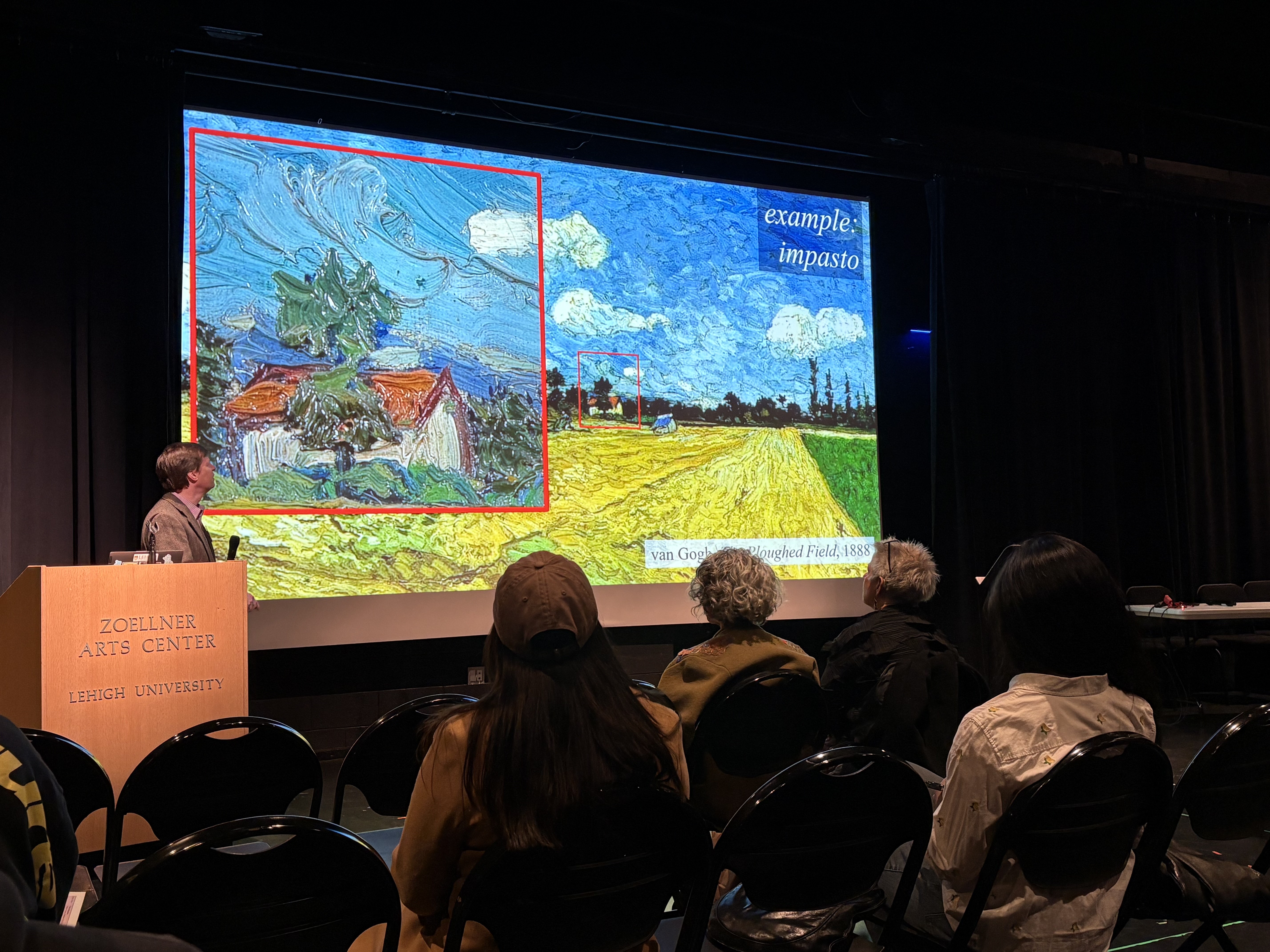 Jim Gilchrist presenting at the Interdisciplinary Research in the Arts Symposium, he is standing in front of a Vincent VanGough painting.