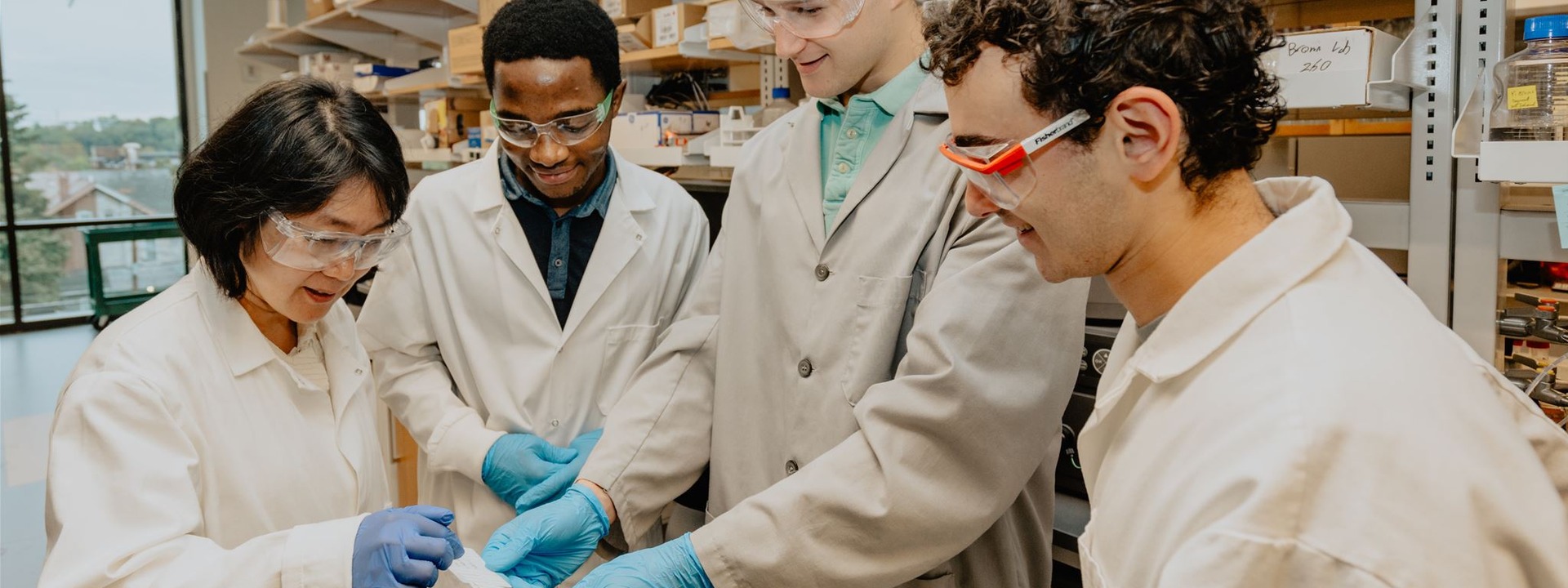 four scientists in lab coats examining a sample