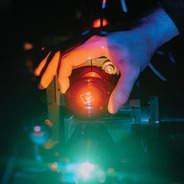 A hand adjusting a sample on a laser table setup
